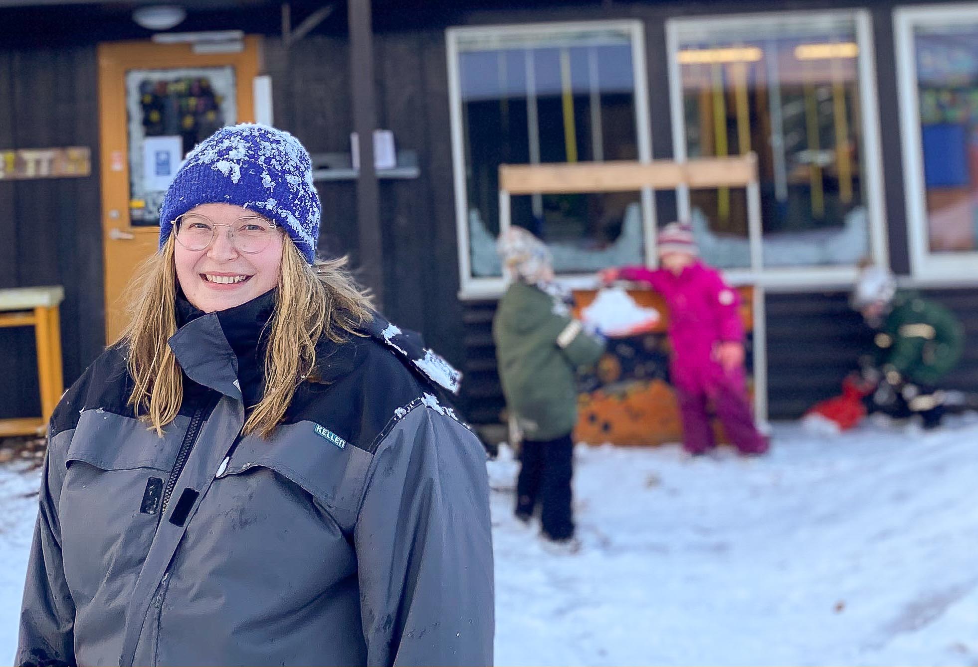 Ung kvinnelig barnehagelærerstudent er i praksis i barnehage. Uteområde, snø.