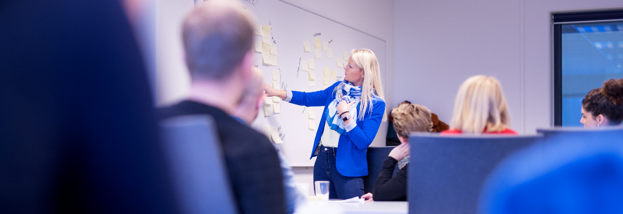 Klasserom med foreleser som peker på whiteboard