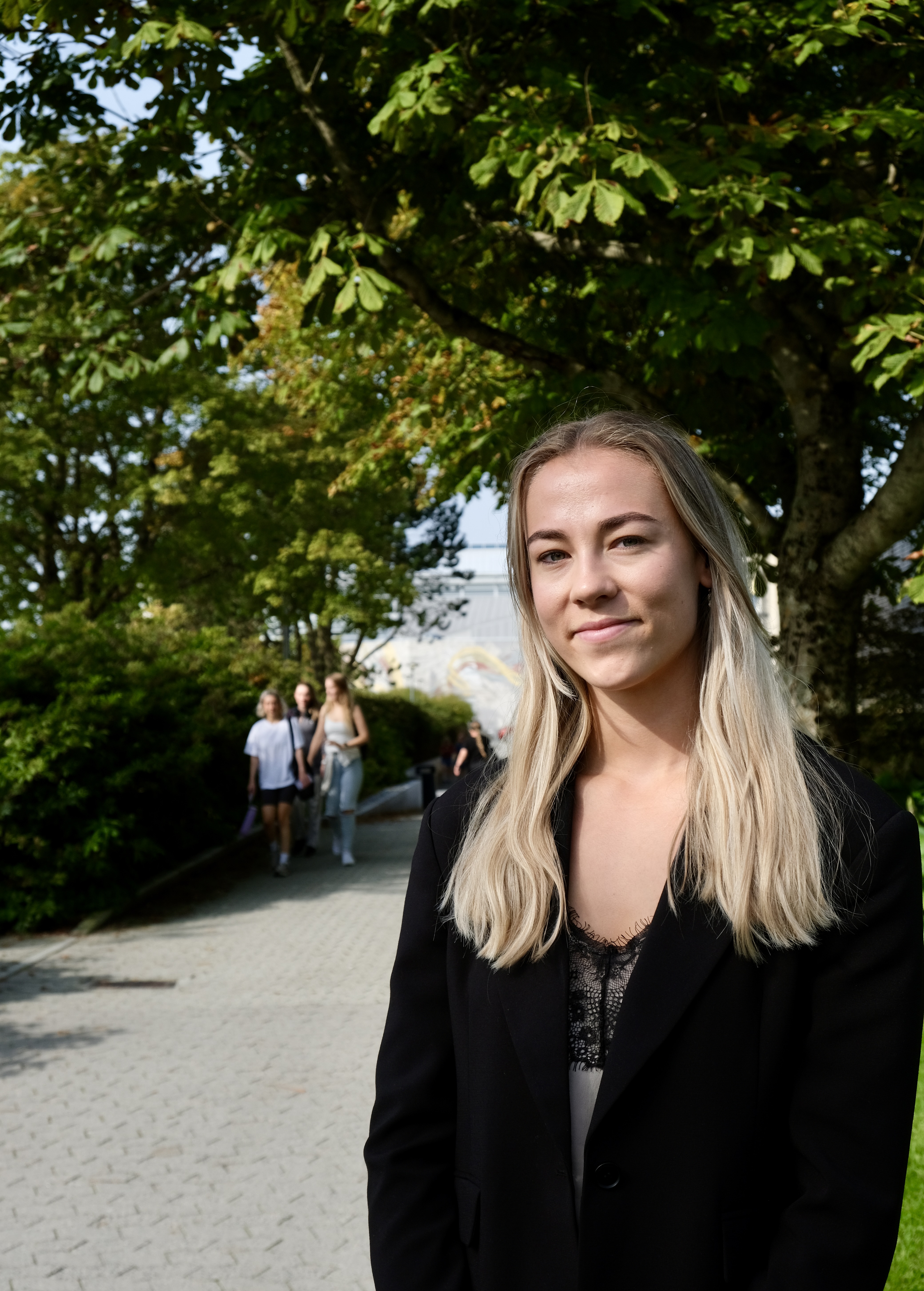 Mona Talberg på campus Ullandhaug med studenter i bakgrunnen