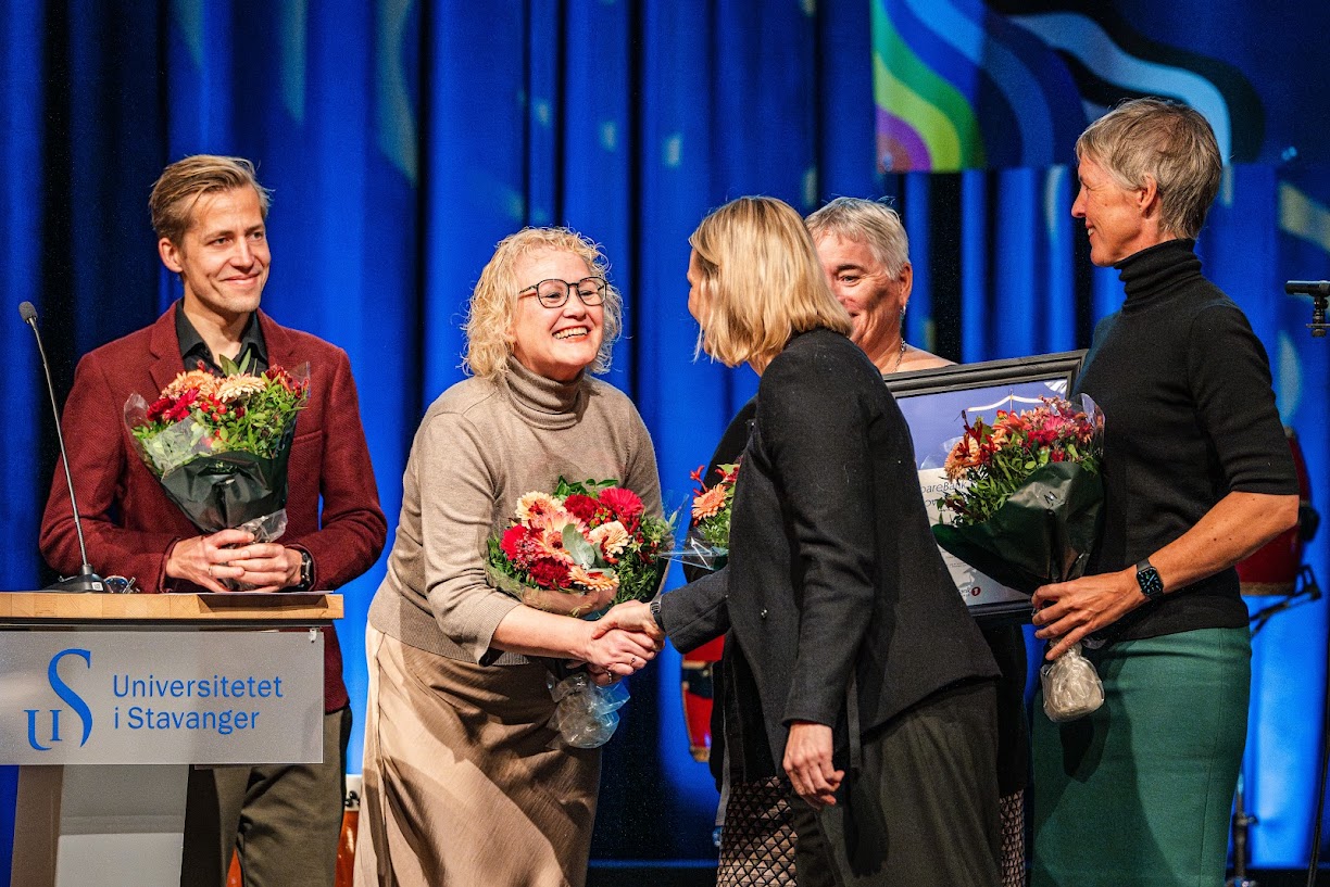 Fem personer på en scene med blomster