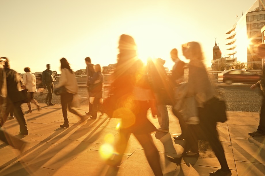 Mennesker går på gate, motlys fra solnedgang