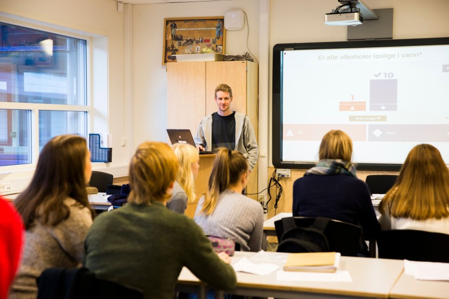 Ung mannlig lærerstudent er i klasserom i praksis. Vi ser en gruppe elever bakfra.