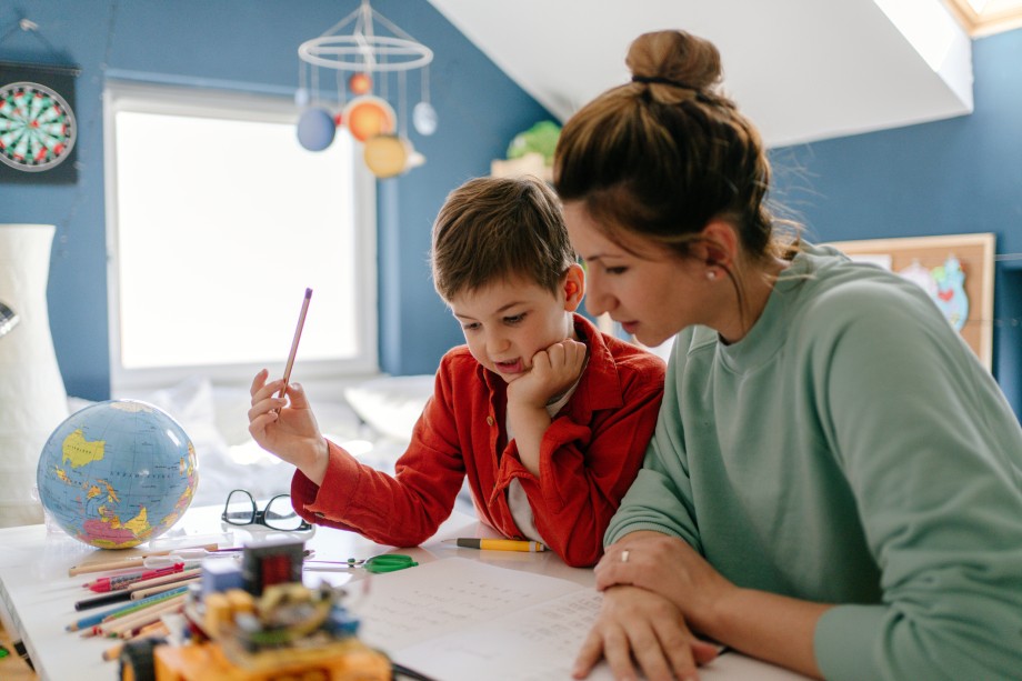 Et barn sitter ved et skrivebord sammen med en kvinne