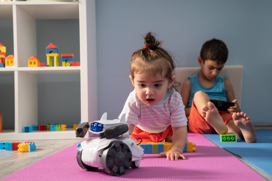 To barn leker med robotleke på gulvet