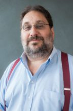 Portrait of a man with brown hair in blue shirt and glasses