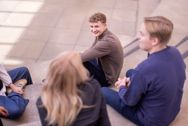 Fire studenter sitter i en gruppe og prater.